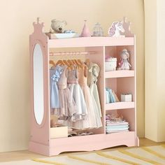 a pink children's wardrobe with clothes and toys on it, next to a mirror