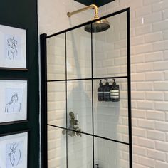 a bathroom with black and white tile, pictures on the wall and a shower head