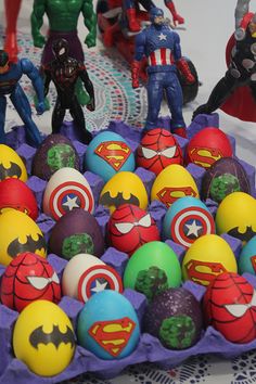 several toy figurines are placed in an egg carton on a table with other toys