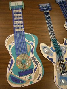 two guitars are sitting next to each other on a table with different patterns and colors