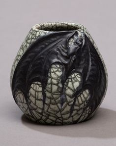 a black and white ceramic vase with a dragon on it's side, sitting on a gray surface