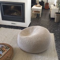 a living room with a fire place and a large round ottoman on the floor in front of a fireplace