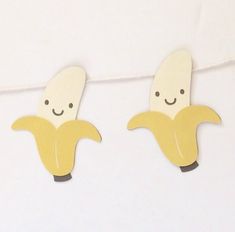 two wooden banana cut outs hanging from a clothes line with string attached to it's sides