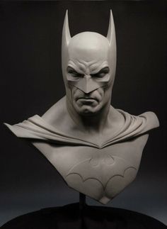 a busturine of batman is displayed on a black stand in front of a dark background