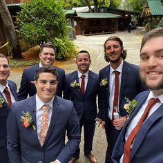 a group of men standing next to each other wearing suits and ties with flowers on their lapels