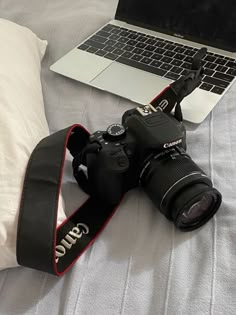 a camera sitting on top of a bed next to a laptop