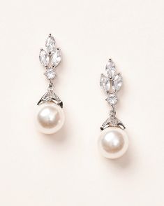 A new twist on a timeless classic, our Bethany Pearl CZ Earrings are crafted with floral shaped CZ designs and a pearl drop. Perfect for the bride who is going for elements of tradition & modern design for her wedding day look. February Wedding, Pearl Earrings Wedding, Groom Dresses, Floral Studs, Bridal Earrings Pearl, Luxury Earrings, Crystal Dangle Earrings, Sparkle Earrings