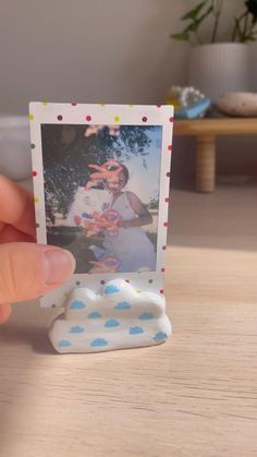 a person holding up a small polaroid with a picture on it's side