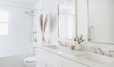 a white bathroom with two sinks, a toilet and a bathtub next to each other