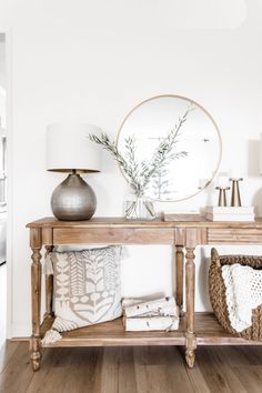 a wooden table topped with a mirror next to a lamp