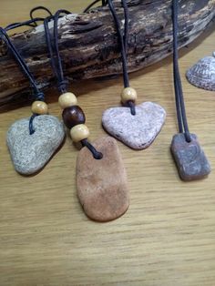 four heart shaped rocks are on a table next to a piece of wood and some beads