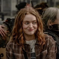 a woman with red hair is smiling and looking at the camera while others stand behind her