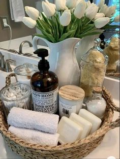 a basket filled with lots of white flowers next to soaps and other bathroom items