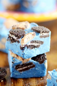 three pieces of blue and black cake sitting on top of a wooden table next to oreo cookies