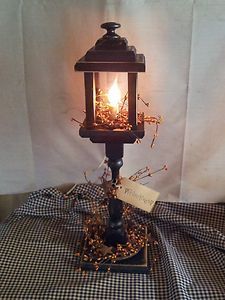 an old fashioned lamp is lit on top of a checkered tablecloth covered table