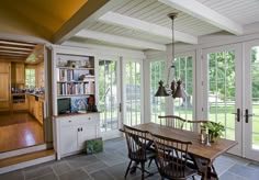 a dining room table and chairs in front of an open kitchen area with french doors