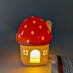 a red and yellow mushroom shaped lamp on a table next to a roll of toilet paper