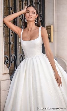 a woman in a white wedding dress leaning against a wall with her hand on her head