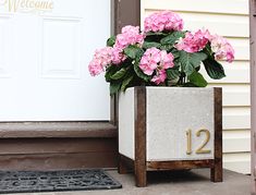 a planter with pink flowers sitting on the front porch