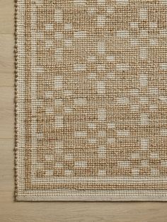 an area rug with white and brown squares on top of wooden flooring, viewed from above