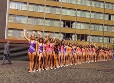 a group of women in bathing suits standing next to each other near a tall building