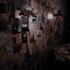 a wall covered with papers and lights in a dark room