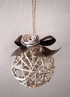 a white ornament with two flowers hanging from it's side on a string