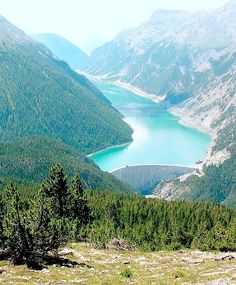 there is a lake in the middle of this mountain range with many trees around it