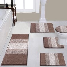 three bathroom rugs on the floor in front of a toilet and bathtub with white fixtures