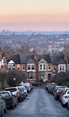 many cars parked on the side of a road in front of some houses and buildings