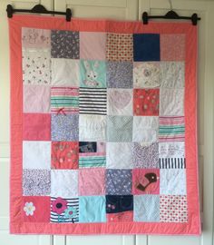 a pink and blue patchwork quilt hanging on the wall