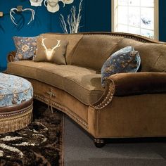 a couch and ottoman in a room with blue walls, rugs and deer antlers on the wall