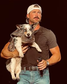 a man holding a dog in his arms and wearing a bandana on it's head