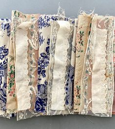 several pieces of cloth with lace on them are lined up against a gray background, one is blue and the other is white