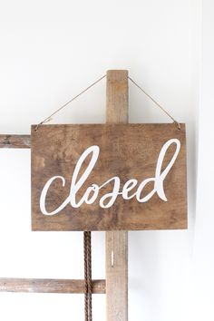 a wooden sign hanging from the side of a wall that says, closed on it