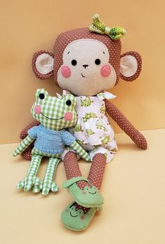 two stuffed animals sitting next to each other on a brown surface with one holding the other's leg