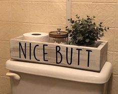 a toilet with a wooden sign that says nice but