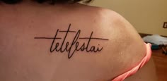 a woman with a tattoo that reads telefatai on her upper back shoulder