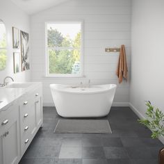 a white bath tub sitting under a window in a bathroom