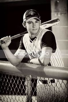 black and white photograph of a baseball player holding a bat over his shoulder in front of a fence