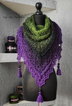 a purple and green knitted shawl sitting on top of a mannequin