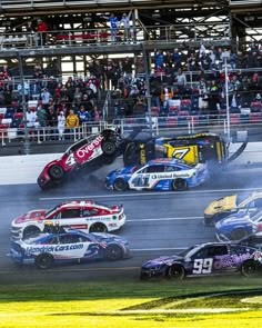 several cars in a race with people watching from the stands