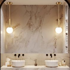 two sinks in a bathroom with marble counter tops and lights on the wall above them