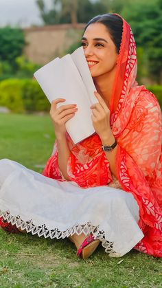 a woman is sitting on the grass reading a book