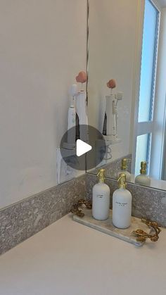 a bathroom sink with soap dispensers on it and a window in the background