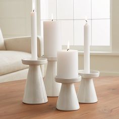 four white candles sitting on top of a wooden table