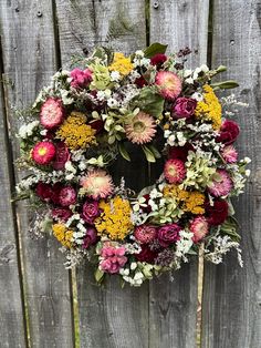 a wreath with flowers is hanging on a fence