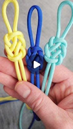 someone holding three different colored ropes in their hand