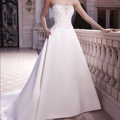 a woman in a white wedding dress leaning on a balcony railing with her hand on her hip