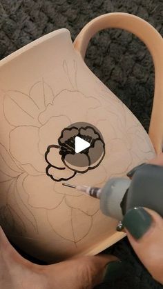 someone is painting a vase with flowers on it